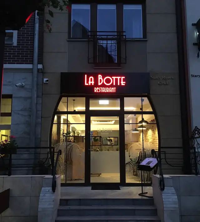 Neon LA BOTTE nad łukowym oknem